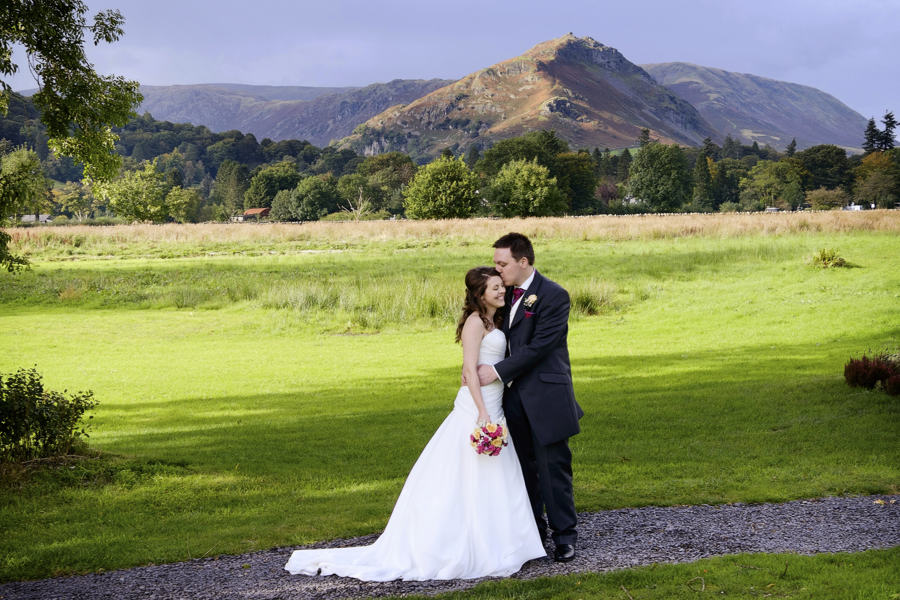 bride & groom with lake district mountains behind at the daffodil hotel, a grasmere wedding venue