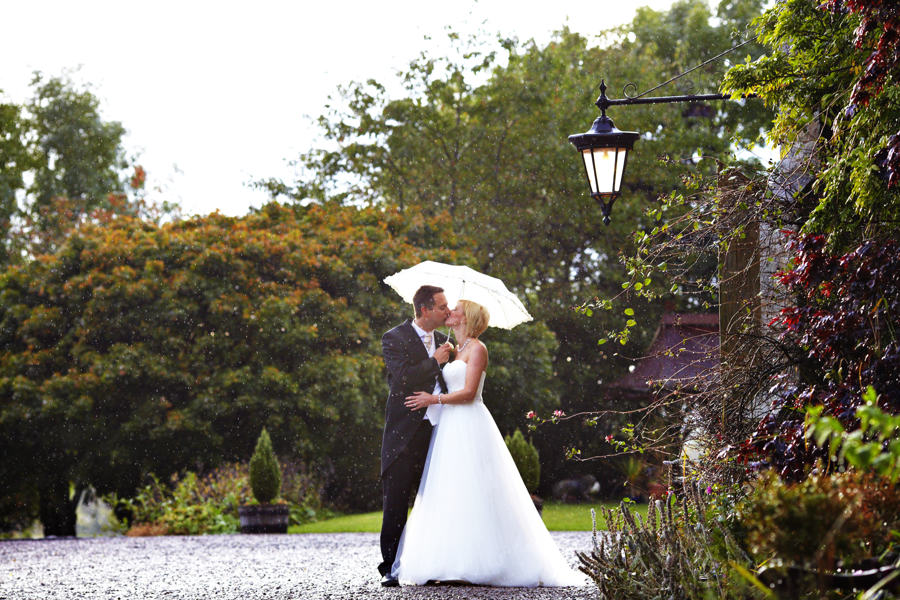 bride & groom in the rain outside augill castle after their wedding ceremony