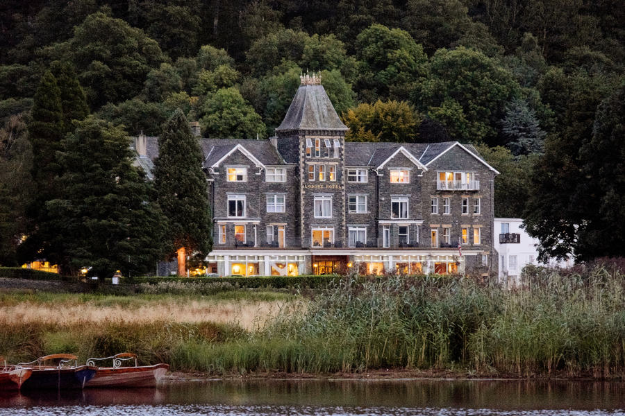 lit up lodore hotel wedding venue with derwentwater and rowing boats in the foreground